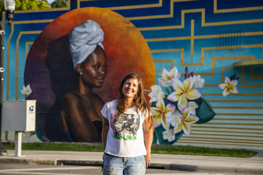 woman standing in front of large outdoor mural
